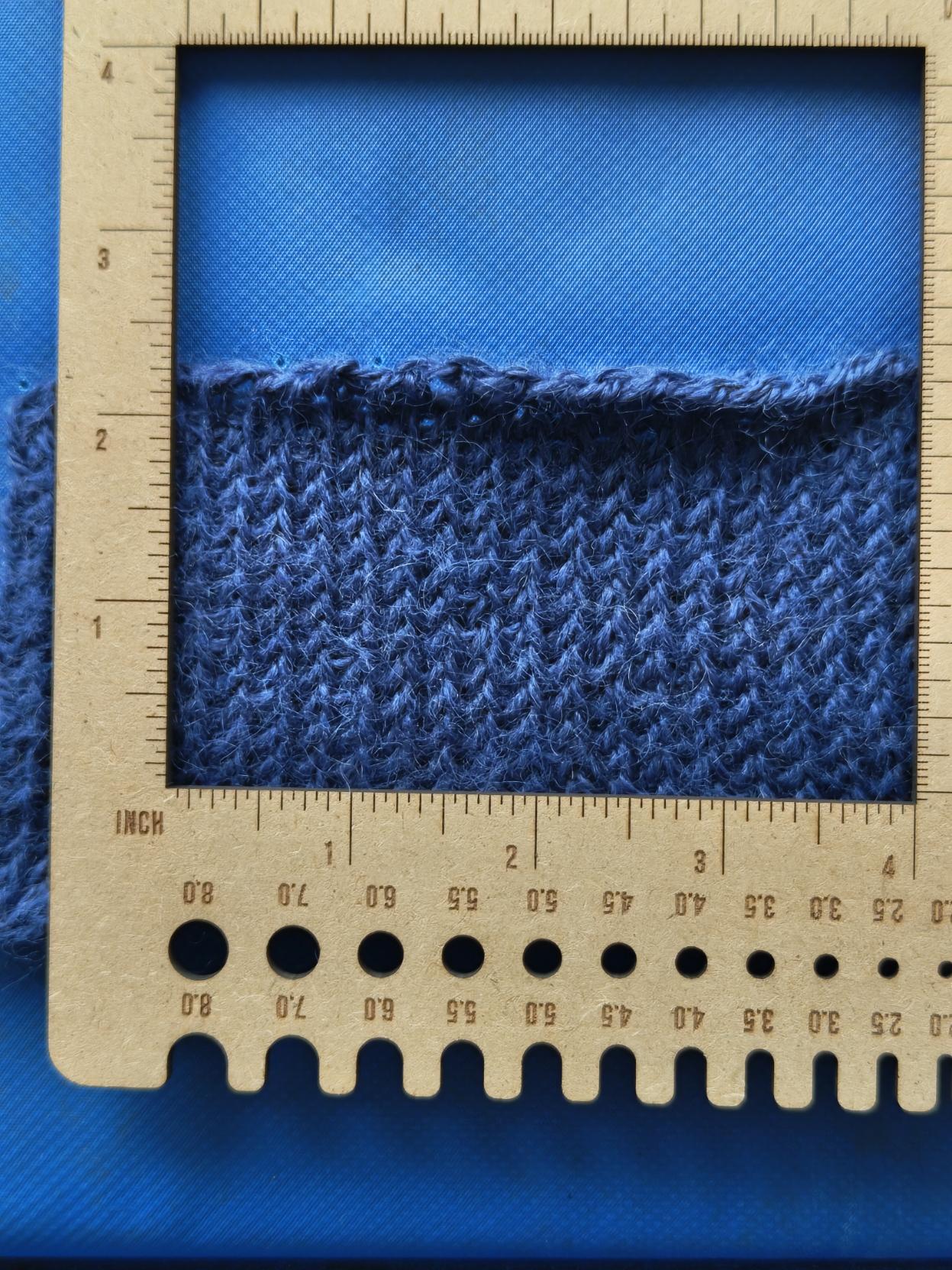 blue yarn tension square on a blue mat background with a ruler overlay