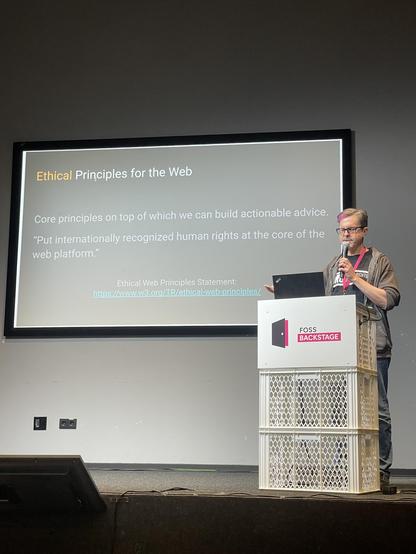 Daniel on stage with a slide up referring to W3C ethical principles for the web.