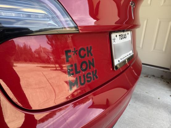 A red Tesla Model 3 with Texas plates and a decal that reads, "F*CK ELON MUSK"