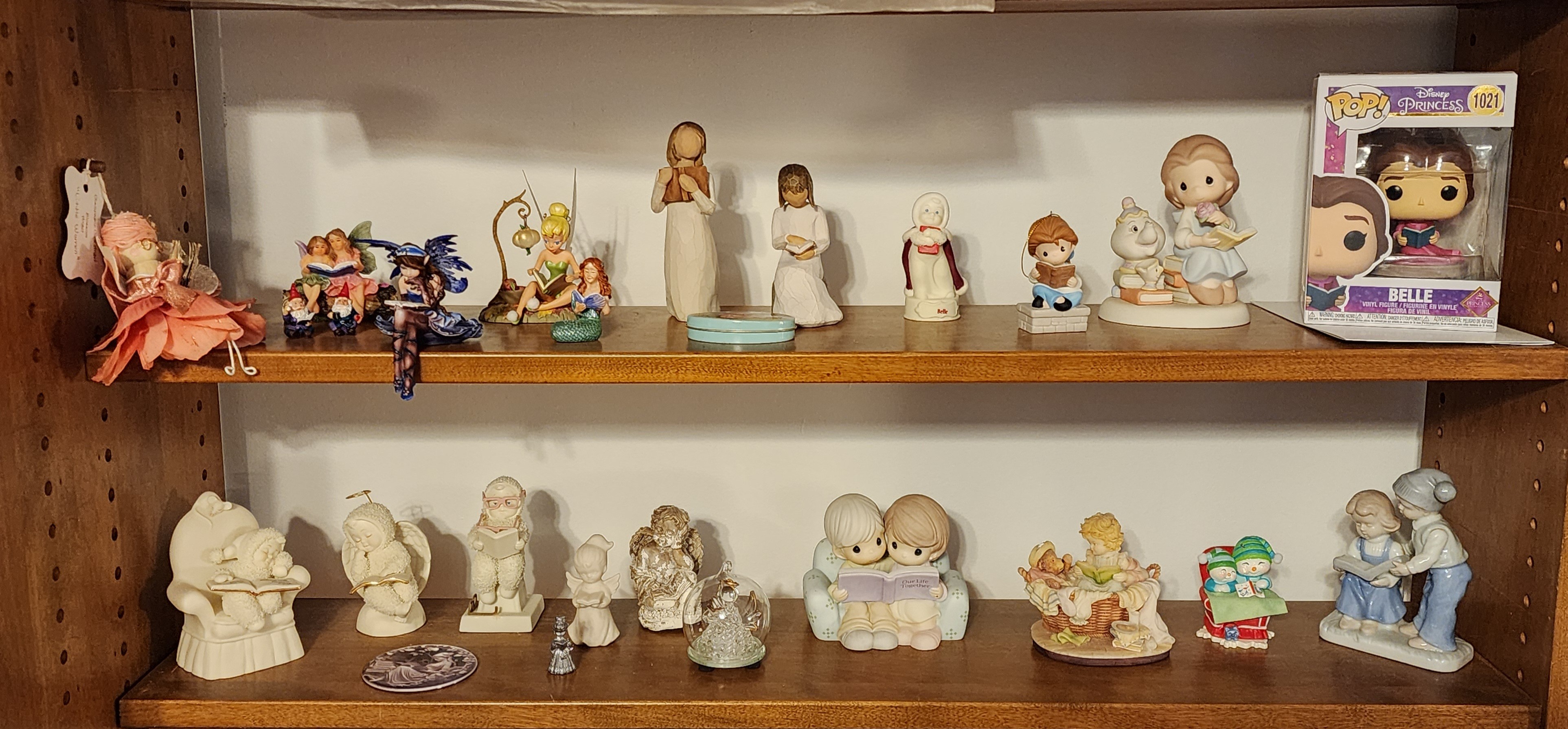 Two shelves of small figurines, all reading a book