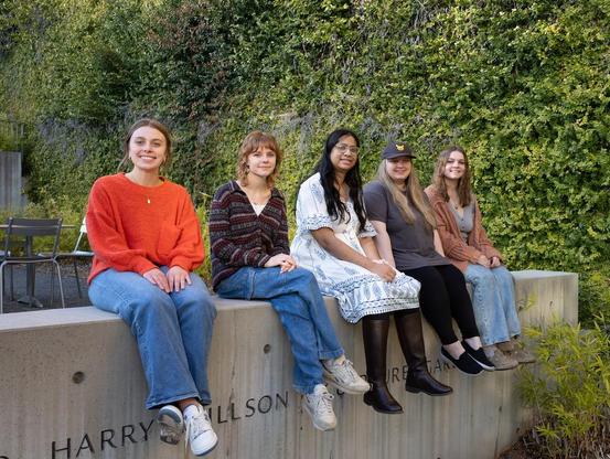 Five of the Georgia Museum of Art's student guides, sitting on a wall in the museum's sculpture garden for a posed photo.
