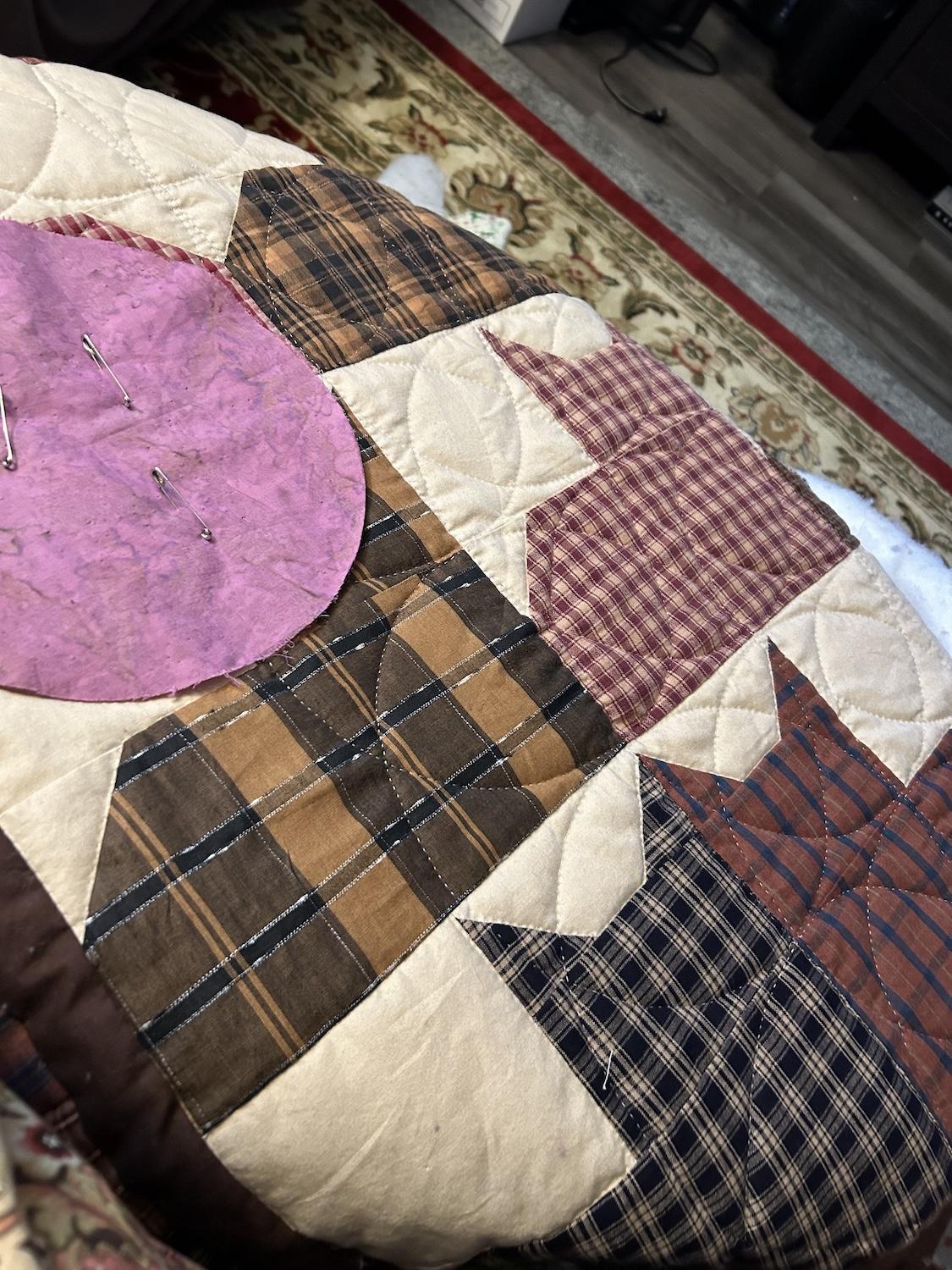 A work in progress photo with a pinkish fabric circle template pinned to a square.