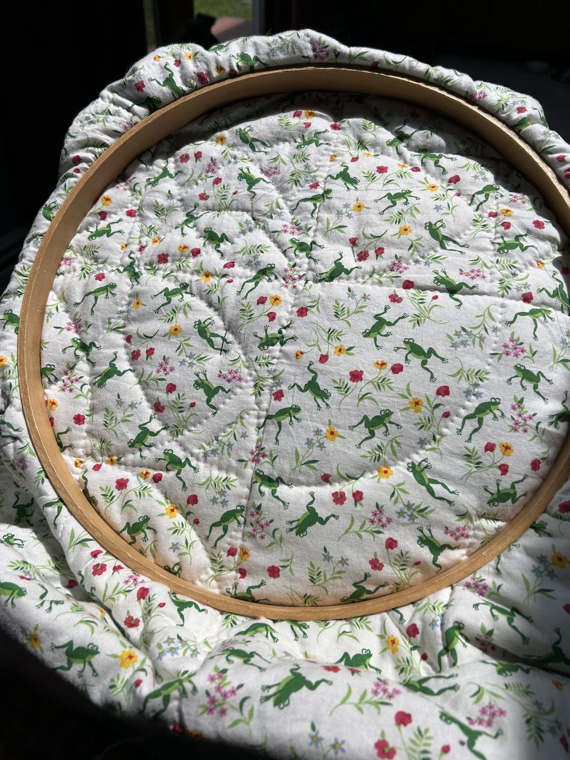 A view of the backing with cute hopping and playing frogs and little flowers.