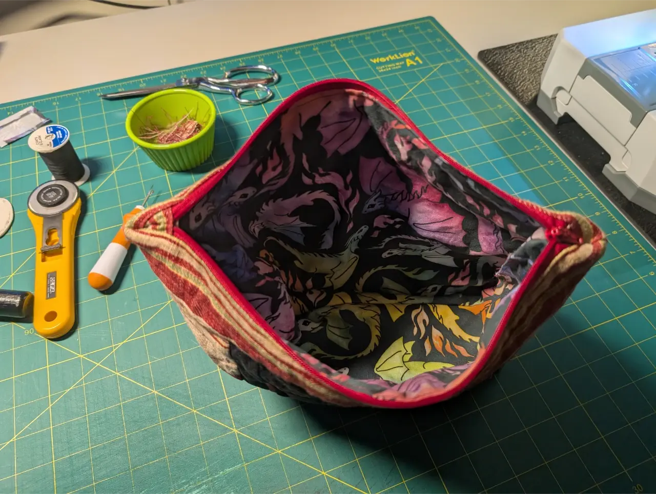 The inside of the zipper bag showing a lining with multicolored dragons on a dark gray background.
