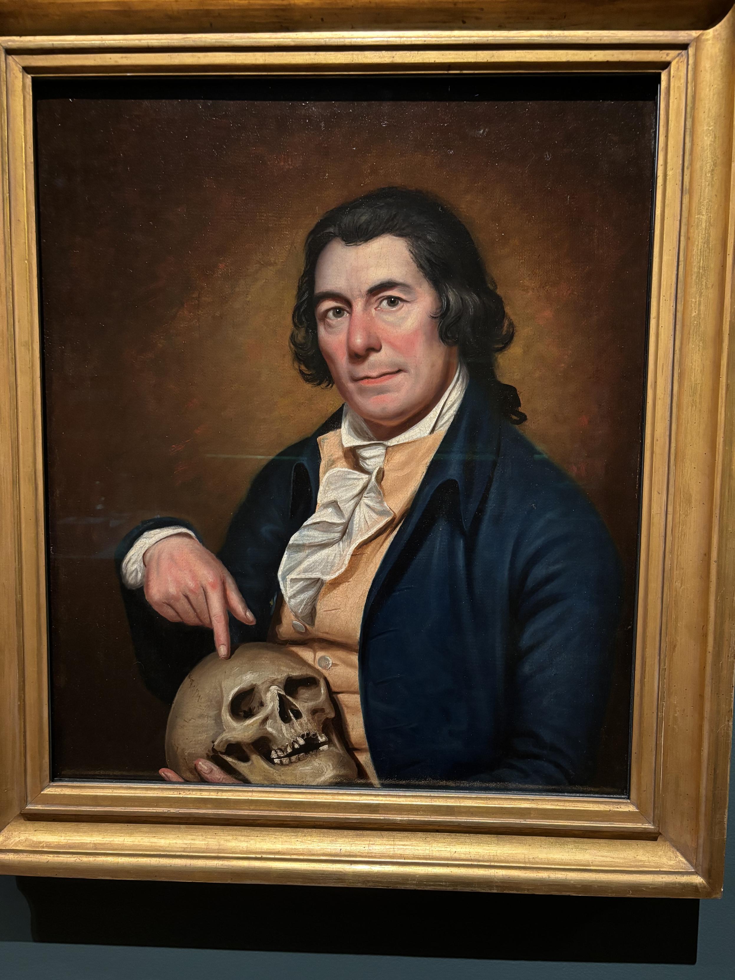 Portrait of John Meer by Rembrandt Peale, a man holding and pointing to a skull.