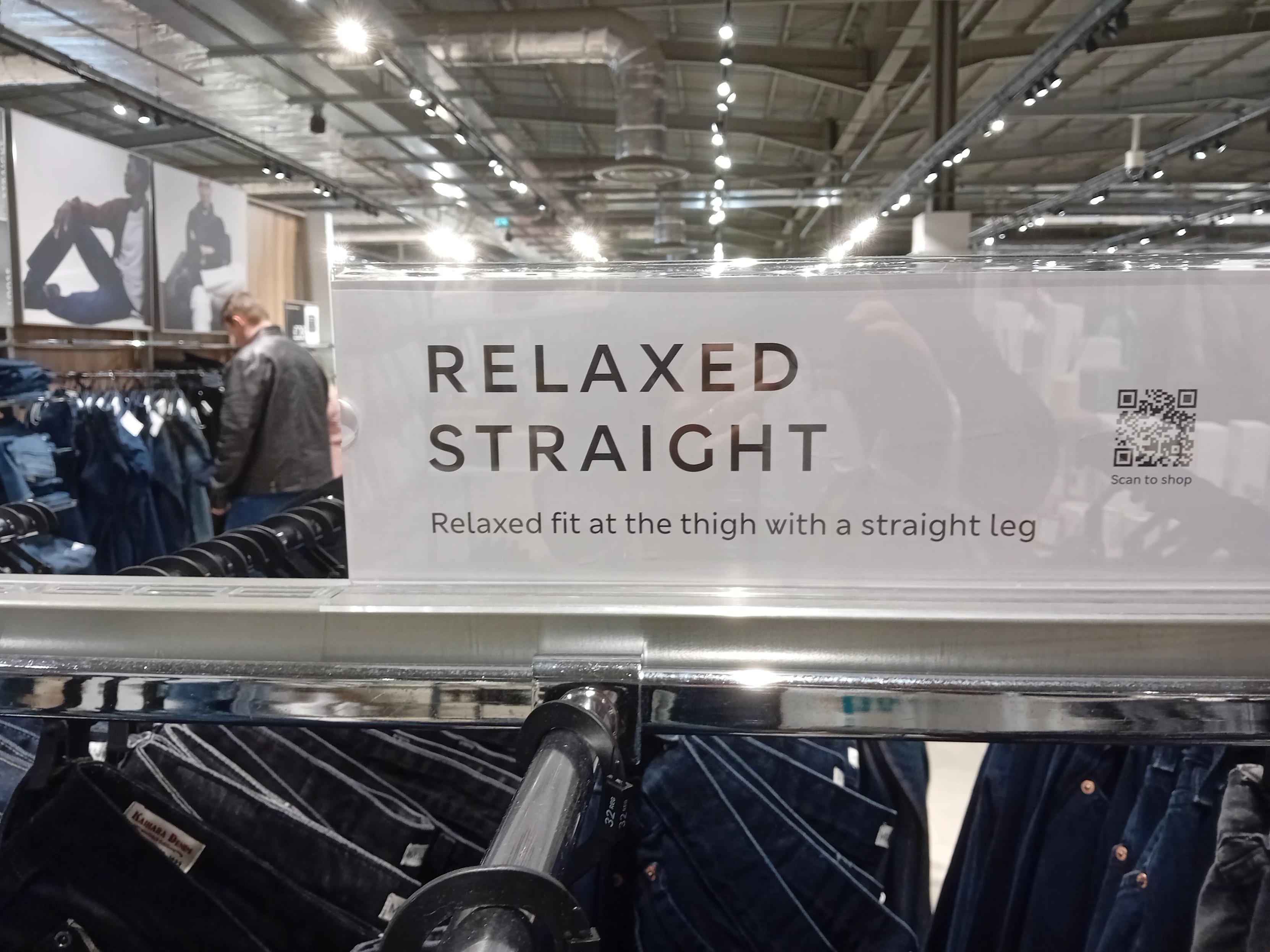 A rack of trousers in a clothing store, underneath a sign that advertises what I presume to be their fit, which is "relaxed straight".