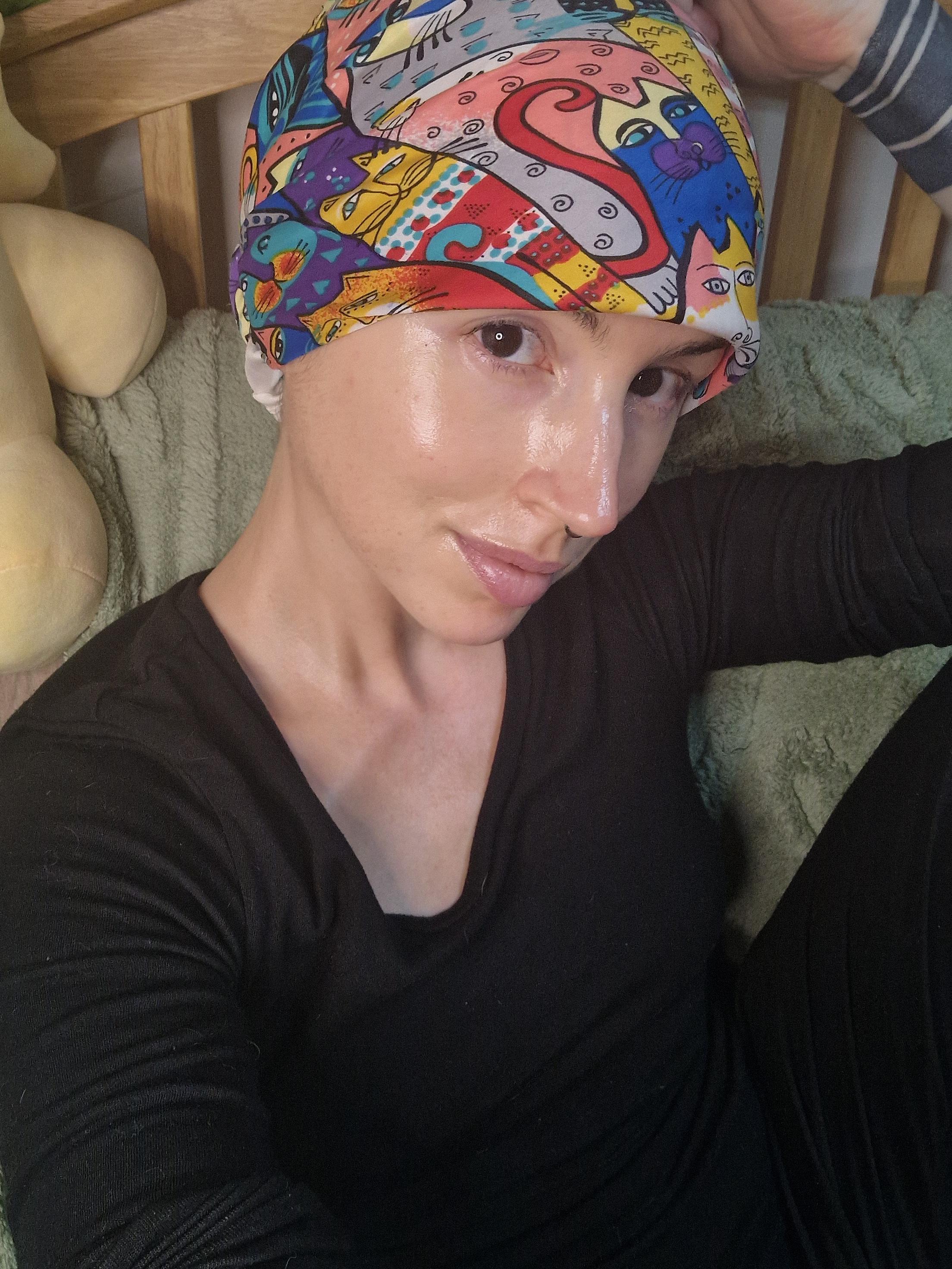 Selfie of me, a slender white person. My hair is under a silk scarf tied around a bun. The scarf is covered in a colourful cat print