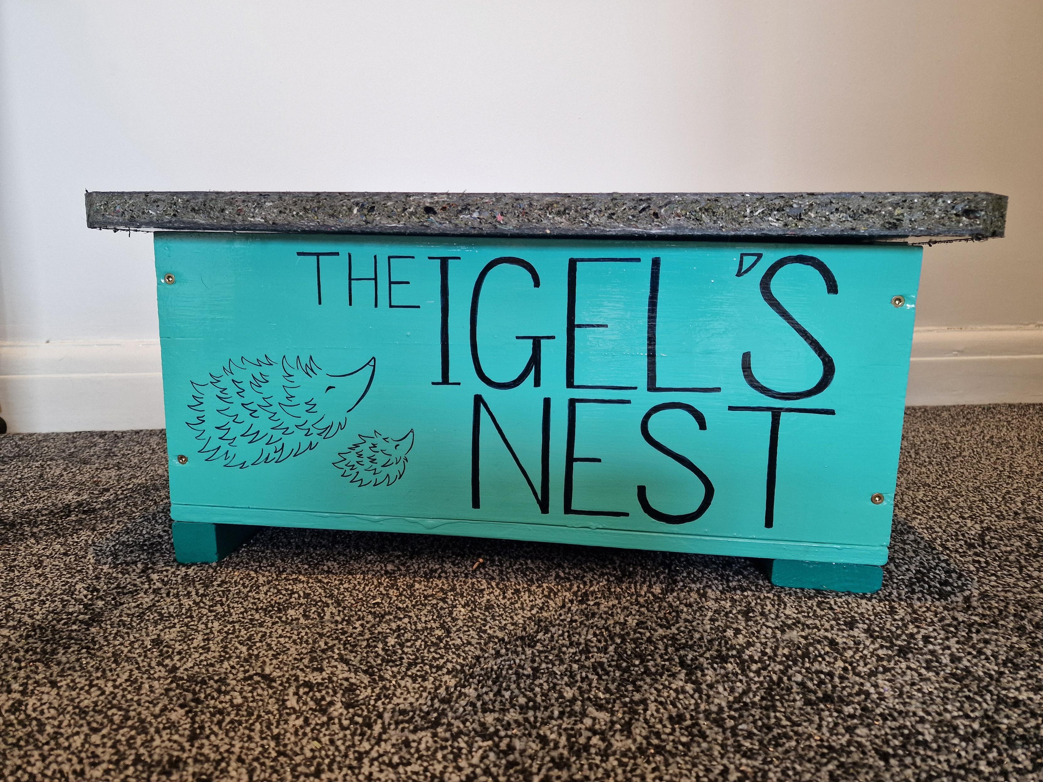 The front of the box with a line drawing of 2 hedgehogs and the words "the Igels nest" written on it in bold writing