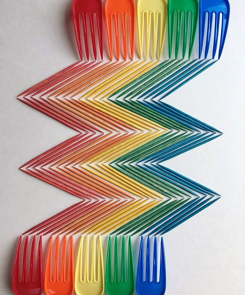 Rows of colorful plastic forks and toothpicks arranged in a zigzag pattern on a white background.