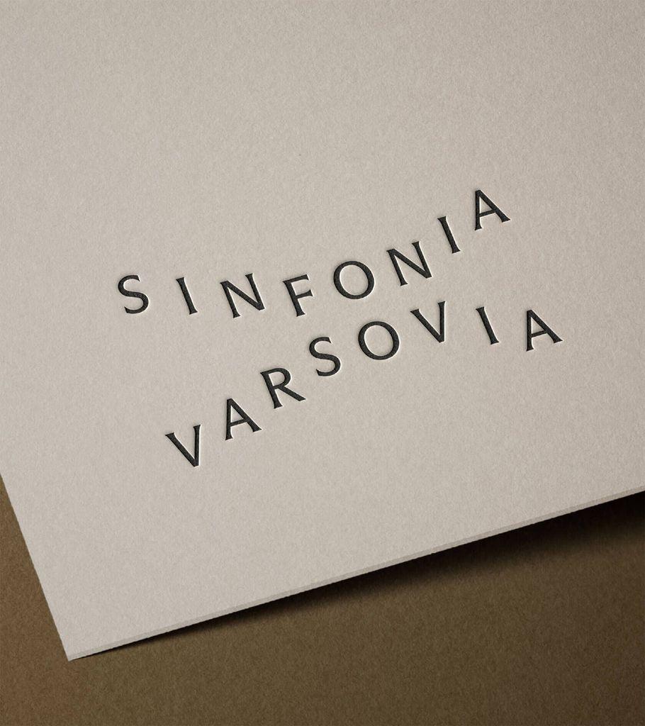 Embossed text "Sinfonia Varsovia" on beige paper with a brown background.