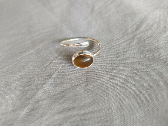 another view of of open end silver ring with a brown oval stone