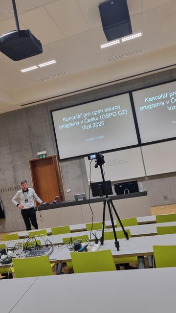 A white man in front of a screen.