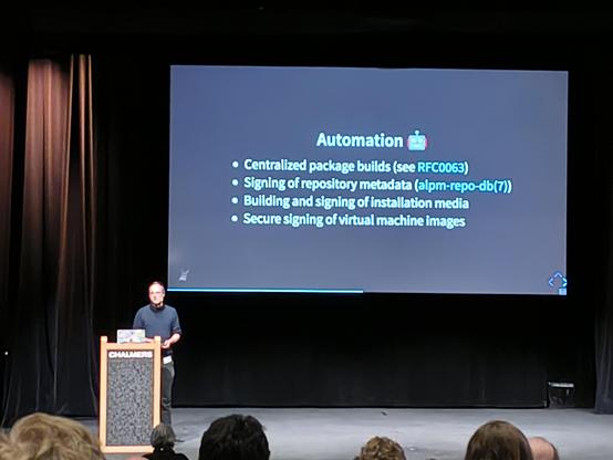 A person on a stage. Behind them - a screen.