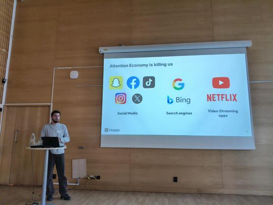 A speaker and a screen that says Attention economy is killing us.