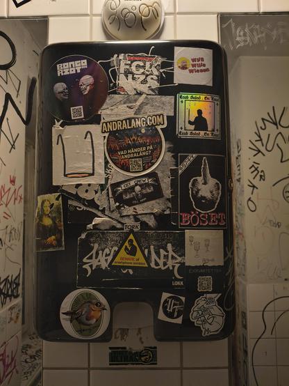 A sticker wall with many stickers. One of them shows a smartphone zombie