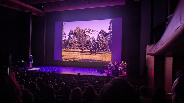 Sam Green and Yo La Tengo onstage at Lincoln Center; kids climb on a jungle gym dome onscreen 