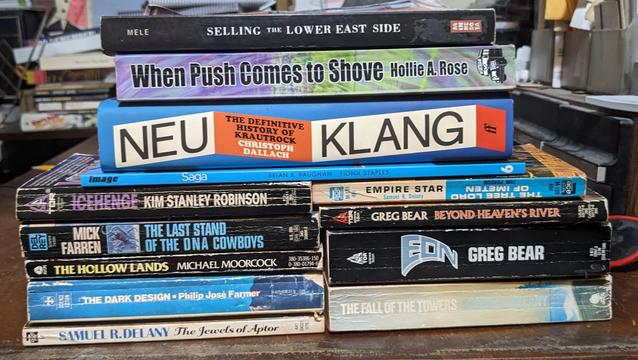 pile of books
Selling the Lower East Side
When Push Comes To Shove 
Neu Klang: the definitive History of Krautrock
Saga #6
Icehenge
The Last Stand of the DNA Cowboys
The Hollow Lands
The Dark Design
The Jewels of Aptor
Empire Star
Beyond Heaven's River
Eon
The Fall of the Towers