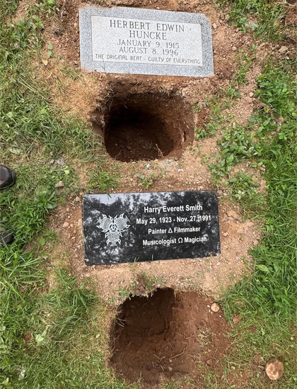 2 holes in ground with plaques for Harry Smith & Herbert Huncke