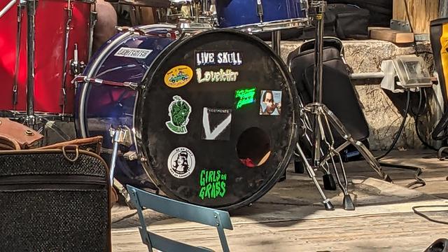 kickdrum with stickers belonging to several bands including Live Skull & Girls On Grass