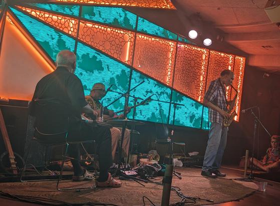 black chamber folk music trio onstage, cooper-moore on percussion, william parker on guimbri, daniel carter on saxophone