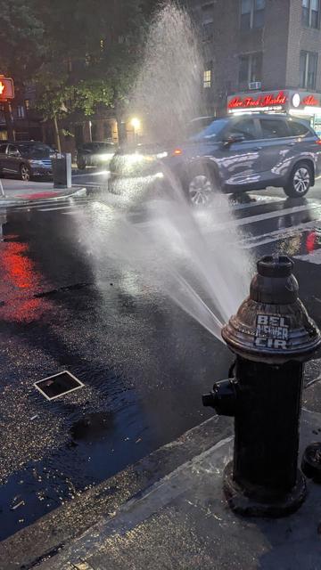 car rolls slowly through open fire hydrant