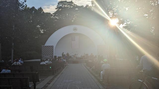 Oneida play in Seuffert Bandshell with sun setting behind them