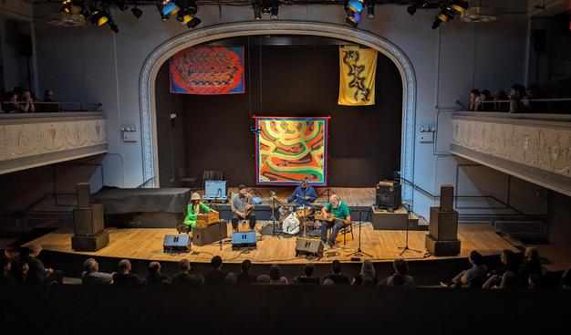 Natural Information Society onstage in Brooklyn with Lisa Alvarado's art