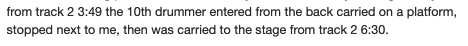 from track 2 3:49 the 10th drummer entered from the back carried on a platform,
Stopped next to me, then was carried to the stage from track 2 6:30.
