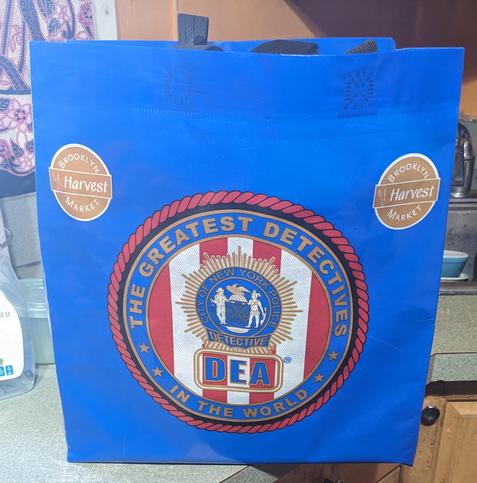 blue shopping bag with DEA logo reading The Greatest Detectives In the World