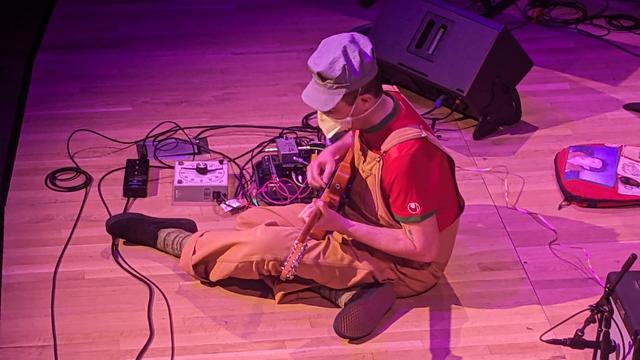 Cyrus Pireh sits onstage and plays guitar