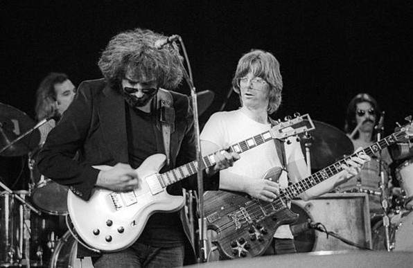 Jerry Garcia jams, Phil Lesh in background, drummers in further background