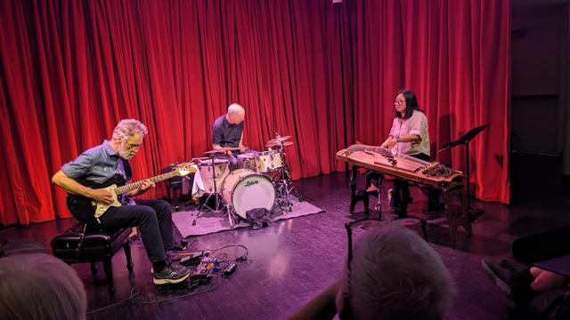 trio of musicians playing guitar, drums, anaeng