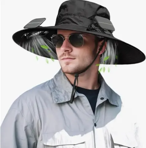 A man wearing sunglasses, a black wide-brimmed bucket hat, and a gray button-up shirt over a dark T-shirt. The hat has two solar panels mounted on the brim and built-in fans underneath, with illustrated airflow and green leaves showing the cooling effect blowing toward his face.