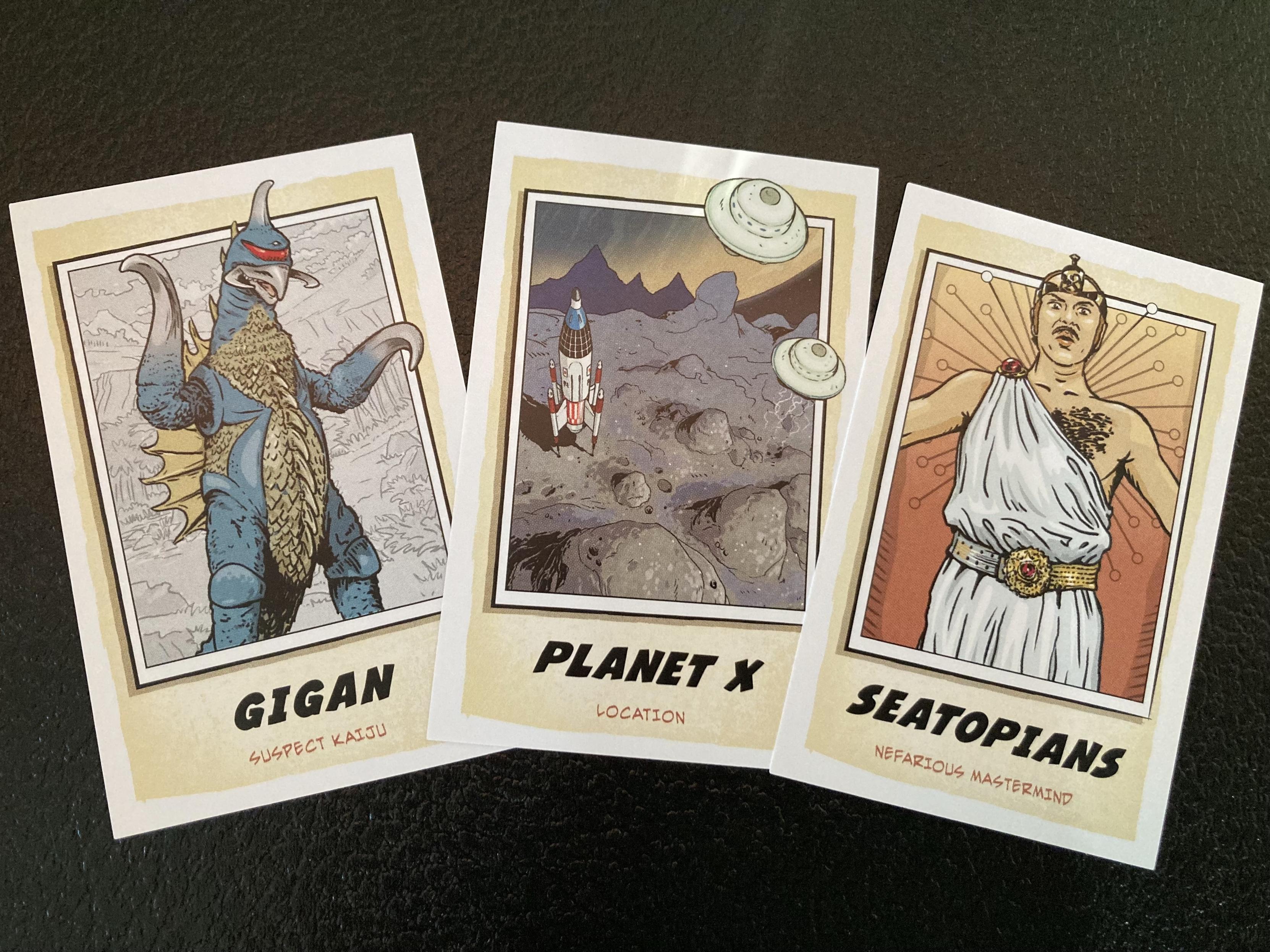 Three game cards with illustrated art. Gigan (kaiju suspect), Planet C (location), Seatopians (nefarious mastermind)