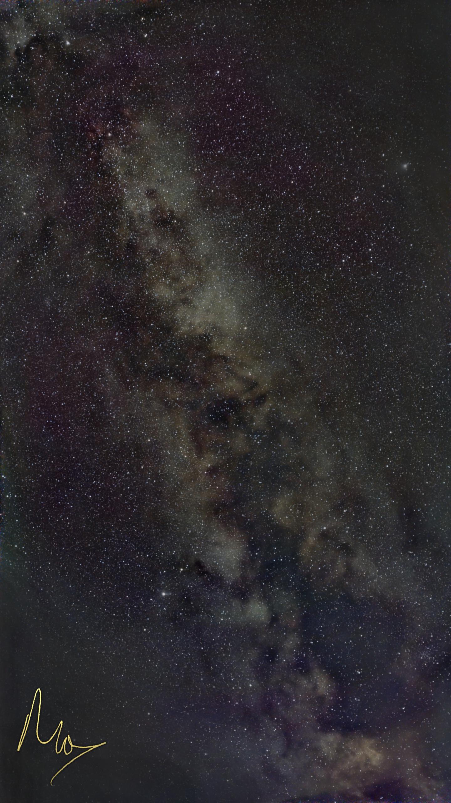 A portrait orientation colour photo of the night sky. The image is full of stars and diagonally from top left to bottom right is a close-up of part of the Milky Way. Top right and bottom left corners have been heavily edited to remove local light pollution.