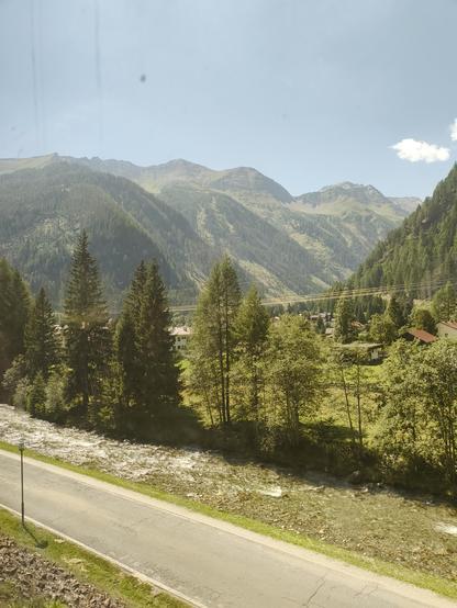Zu sehen ist ein Foto, aufgenommen aus einem Zugfenster auf die österreichischen Alpen.