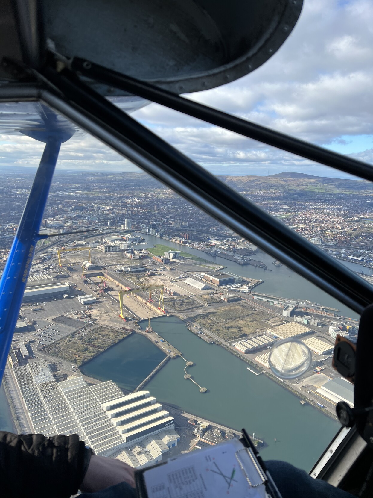 The iconic yellow cranes located at Belfast Docks. They are framed by the window of a light airplane.