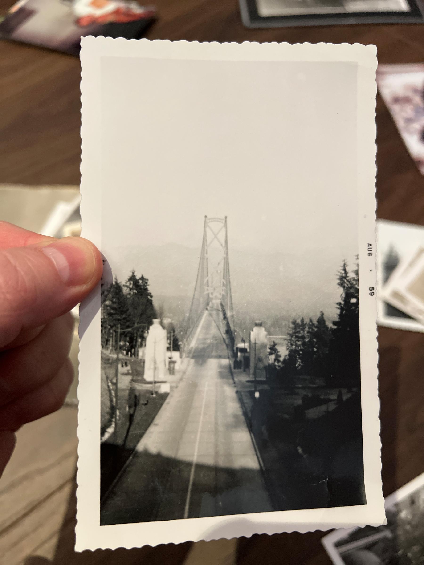 Chad holds up an old black and white photo showing the entrance of the bridge, probably from the overpass, looking straight across to north van. The north shore mountains are faint in the distance.