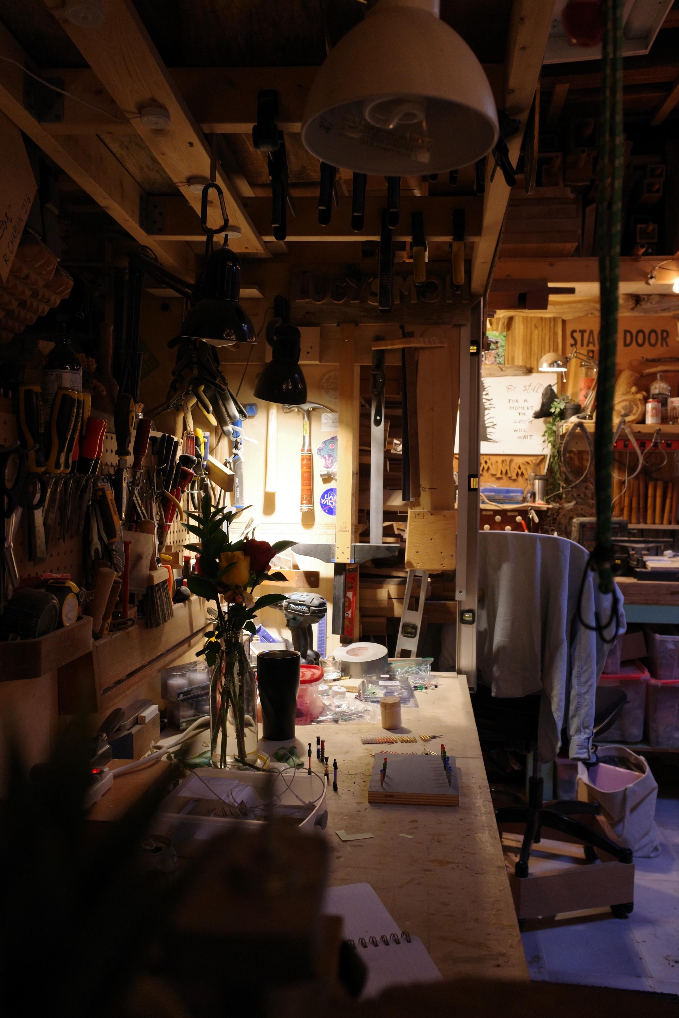 A woodworkers bench in low light with a plethora of tools