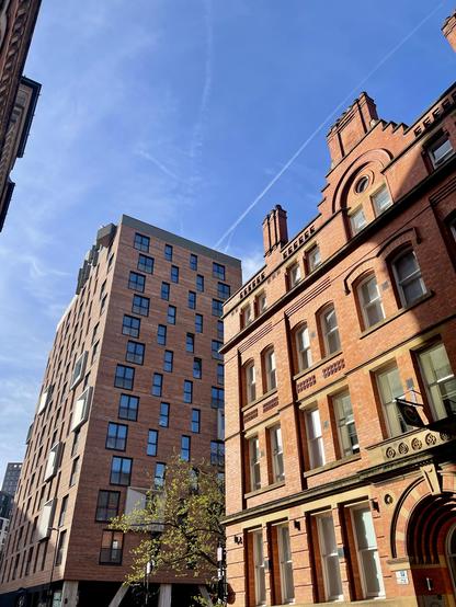 Tall red brick industrial buildings against a blue sky. 