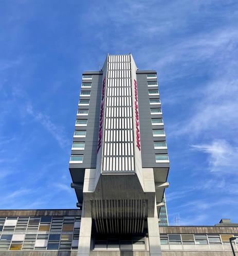 A tall brutalist building shot from below. Deep blue sky. 