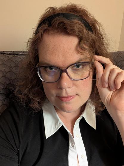 Christine holds onto her glasses and looks into the camera