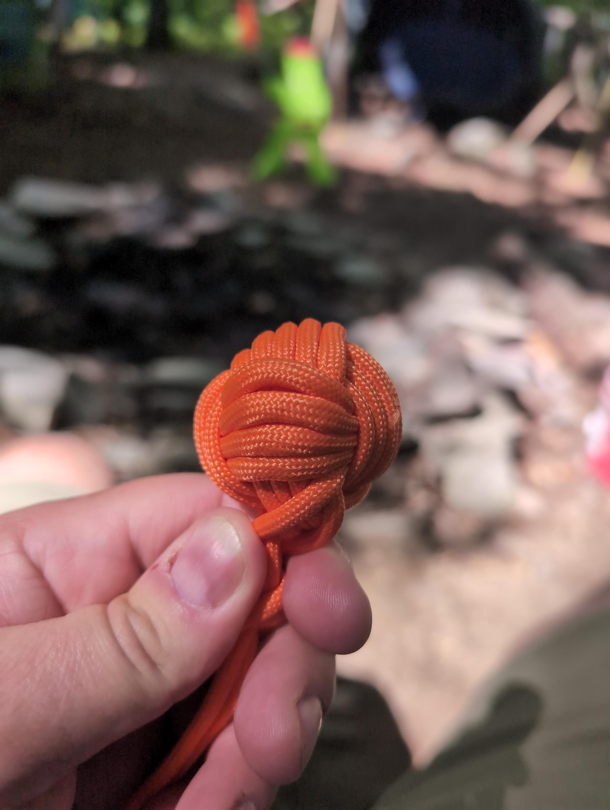 A mediocre "monkey's fist" made of orange paracord tied around a roughly 1" mostly-round rock.