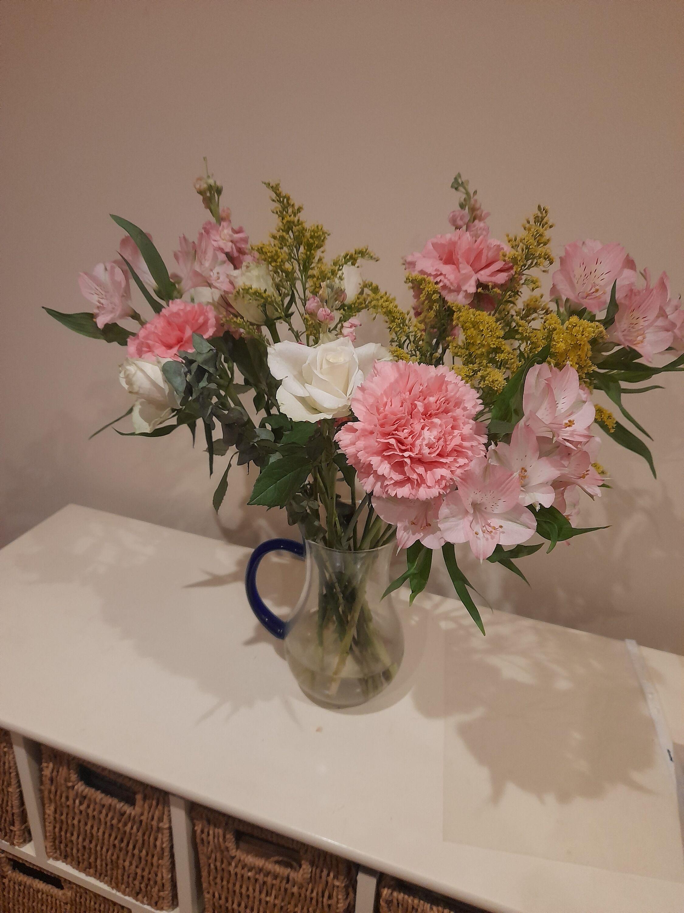 a glass jug with beautiful pink and white flowers in it.