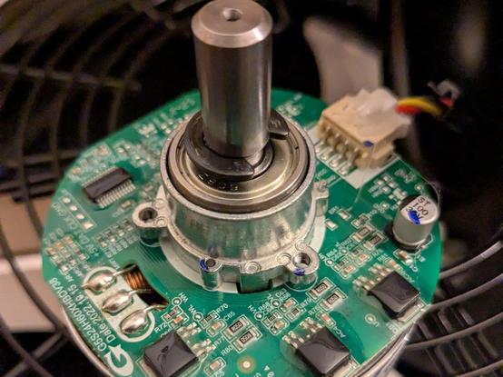 Brushless motor with a green PCB mounted on the front. 3 power driver ICs are visible in the foreground, clearly potted on some epoxy or similar coating.