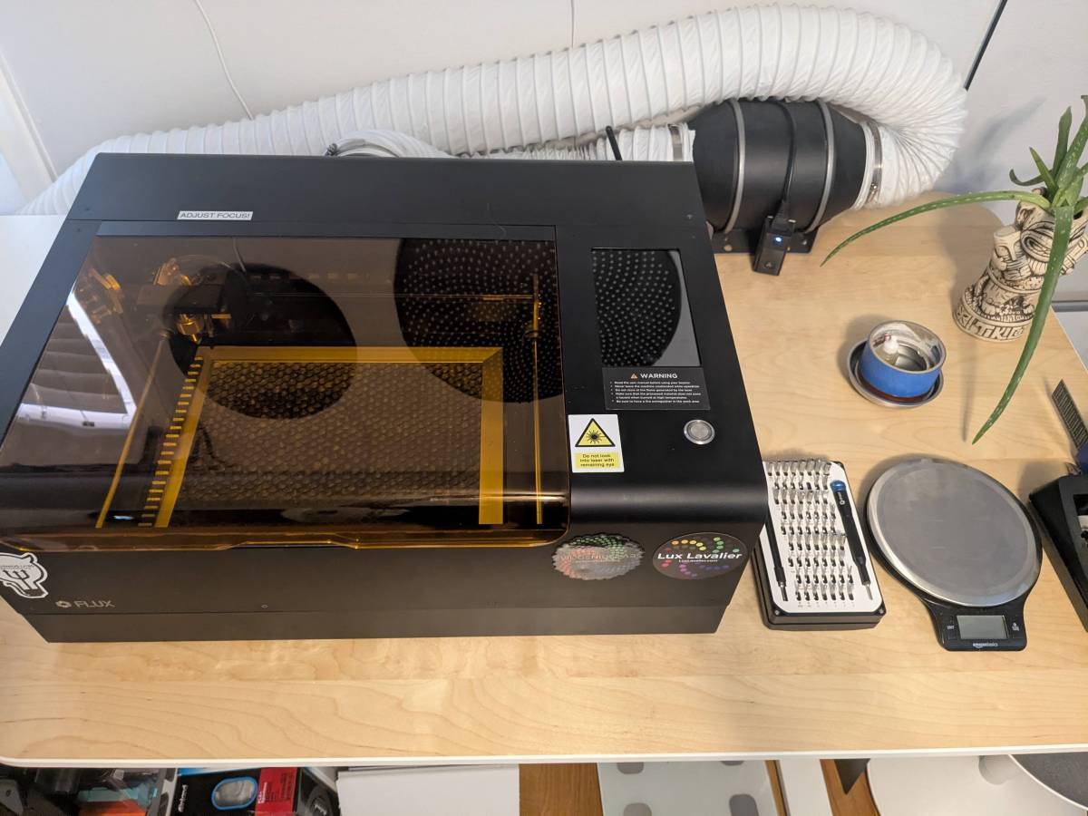 Photo of a small desktop laser cutter on a table.