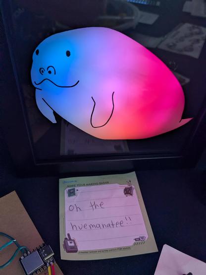 A cartoon manatee lit up blue/purple/red labeled "oh the huemanatee!!"