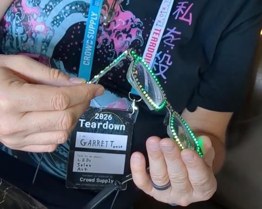 a person holding a glasses frame made out of PCBs with LEDs with prescription lenses