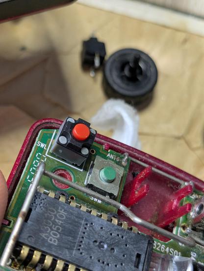 inside the mouse, showing the new button with a red cap. the old button and mouse wheel are blurry in the background.
