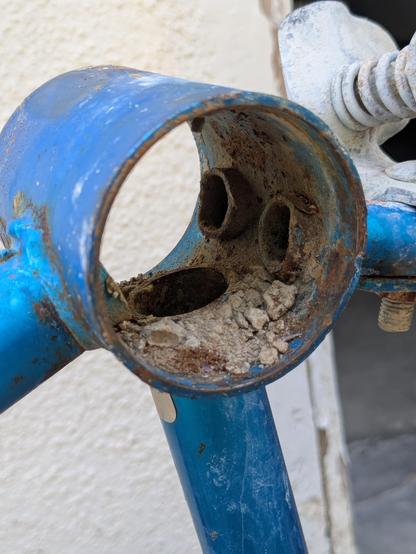inside the bottom bracket of a blue bicycle. chunks of clumped alkaline dust are visible.